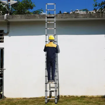 Thợ đứng trên thang nhôm rút tựa vào tường